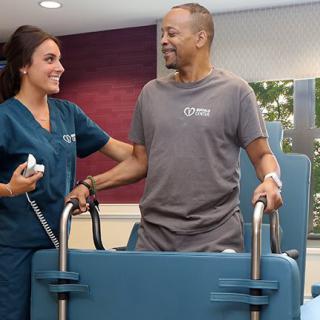 A nurse assists a patient with physical therapy exercises in a medical facility.