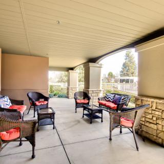 A cozy patio with wicker furniture and red cushions, set under a covered area.