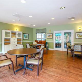 A cozy community room with seating arrangements, tables, and a shelving unit.