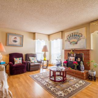 Cozy living room with armchairs, a fireplace, and a coffee table on a patterned carpet.