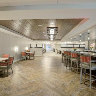 A modern restaurant interior with dining tables and bar seating.