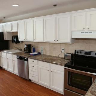 A modern kitchen with white cabinets, stainless steel appliances, and granite countertops.