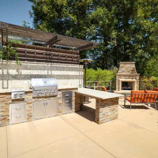 A beautifully designed outdoor kitchen with a grill and cozy seating area, perfect for summer gatherings.
