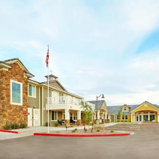 A view of a welcoming residential building with an American flag in front, set against a cloudy sky.