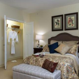 A cozy and elegantly decorated bedroom with a neatly made bed, closet, and ambient lighting.