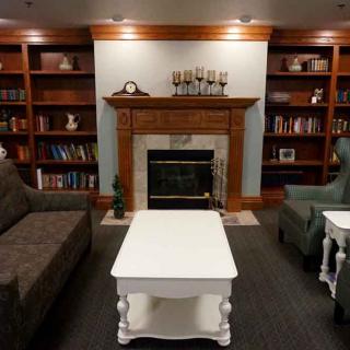 A cozy living room with a fireplace, surrounded by bookshelves and furnished with comfortable sofas and a white coffee table.