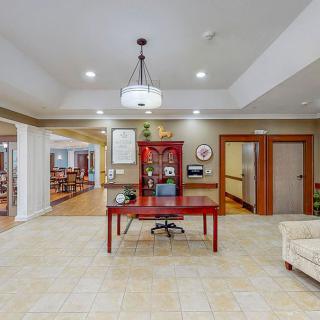 A welcoming lobby area with a central red desk, chandelier lighting, and comfortable seating.