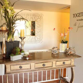 A beautifully decorated entryway with a wooden table, mirror, plants, and candles.