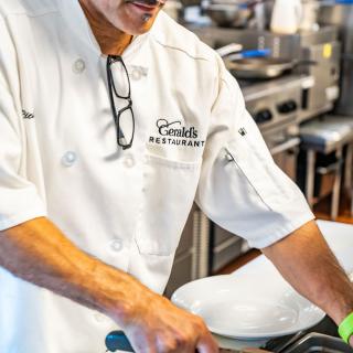 A chef in a white uniform preparing food in a professional kitchen.