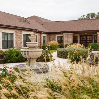 A beautiful house with a well-maintained garden and a central fountain.