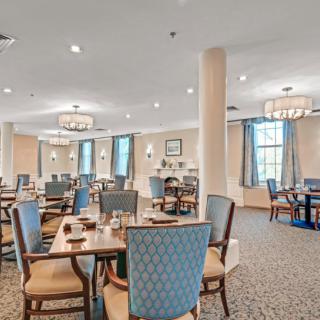 An elegant dining room with neatly arranged tables and chairs, featuring warm lighting and tasteful decor.
