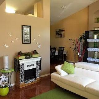 A modern living room with a white sofa, decorative fireplace, and green accents.