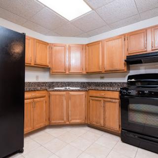 A cozy kitchen featuring wood cabinets, black appliances, and a spacious countertop.