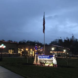 A flag stands tall amidst festive holiday decorations outside a building during the evening.