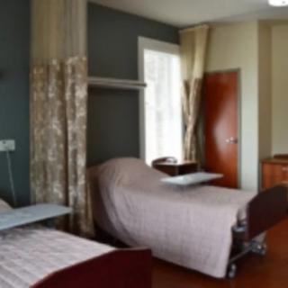 A hospital room with two beds and privacy curtains.