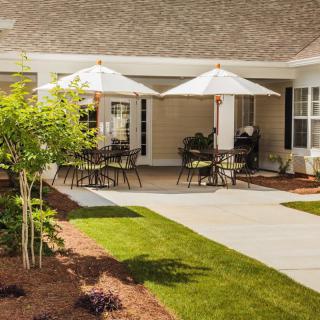 A well-manicured patio area with outdoor furniture and umbrellas, surrounded by a beautifully landscaped garden.