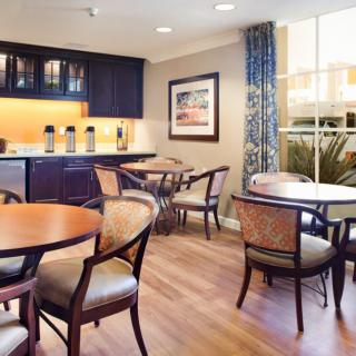 A modern cafe seating area with tables, chairs, and a coffee station.