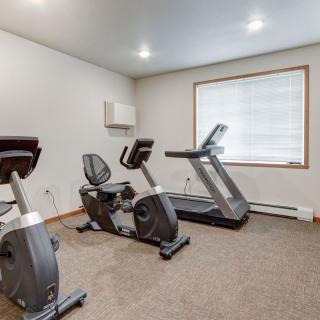 A small gym with a treadmill and stationary bikes.