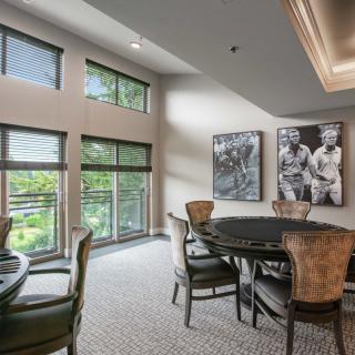 A modern dining room with large windows, stylish chairs, and artwork on the walls.