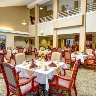 A well-lit dining area with neatly arranged tables and chairs, featuring elegant decor.