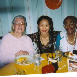 A group of three people smiling at a dining table.