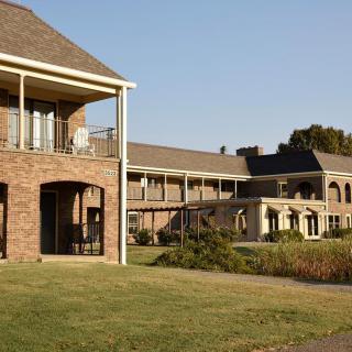 A large brick house with multiple levels and a spacious lawn.