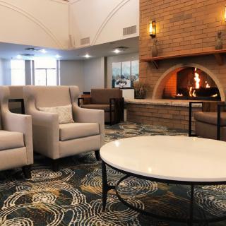 A cozy living room with modern decor featuring a fireplace, armchairs, and a coffee table.