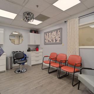 A modern waiting room with orange chairs and stylish decor.