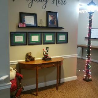 A cozy entrance area featuring framed documents, a decorative table, and festive lighting.