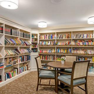 A cozy library with bookshelves, a table, and chairs for reading.