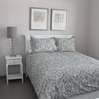 A neatly arranged bedroom with a patterned duvet, bedside table, and lamp.