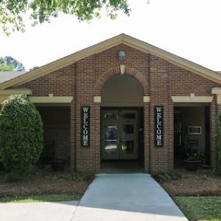 A welcoming entrance to a brick building, surrounded by well-maintained landscaping.