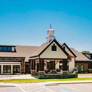 A modern building with a pitched roof and an entrance under a clear blue sky.