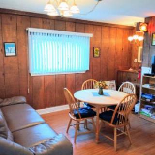 A cozy living and dining area featuring wood paneling, a comfortable couch, and a round dining table with chairs.