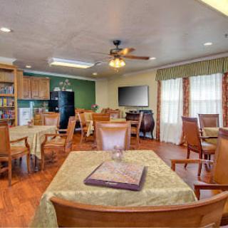 A cozy dining area with wooden tables and chairs, adjacent to a kitchen.