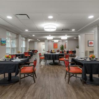 A spacious and modern dining area featuring elegantly set tables with colorful chairs.