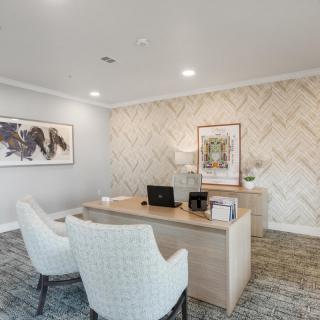 A modern office with a minimalist desk and chairs, adorned with stylish artwork on the walls.