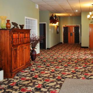 A warmly lit hallway with decorative carpet and wooden furniture.