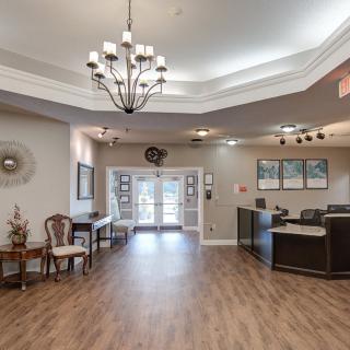 A spacious lobby area with a chandelier, wooden flooring, and a reception desk.