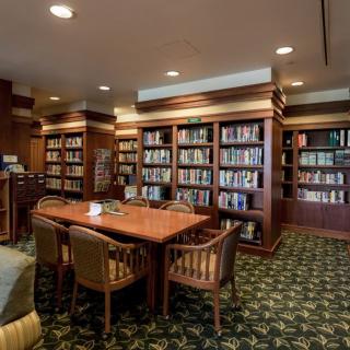 A cozy library interior with wooden bookshelves, a table, and chairs for reading.