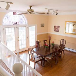 A spacious and inviting dining room with a wooden table set for gatherings, featuring natural light and tasteful decor.