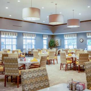A modern dining room with neatly arranged tables and chairs, featuring bright lighting and contemporary decor.