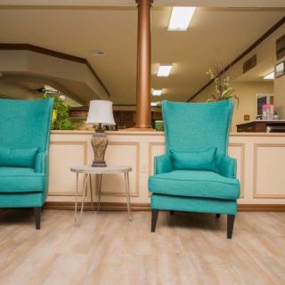 Two teal chairs in a cozy lobby setting with a small table and lamp.