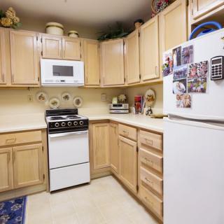 A cozy kitchen with wooden cabinets, equipped with a stove, microwave, and refrigerator.