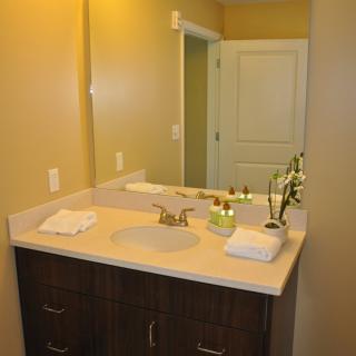 A neat bathroom vanity area with a mirror, sink, and neatly arranged towels.
