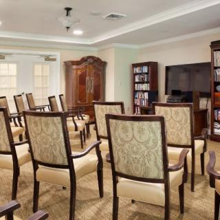 A well-organized conference room with rows of upholstered chairs facing a television and bookshelves.