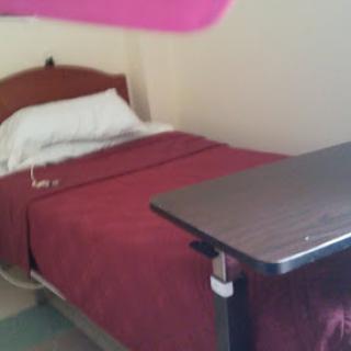 A simple room featuring a bed with red bedding and a small table.