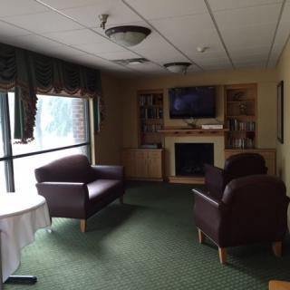 A cozy lounge area with comfortable chairs, a television, and a fireplace.