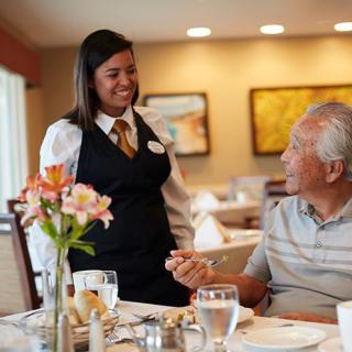 A waitress smiling and interacting with a customer in a restaurant setting.