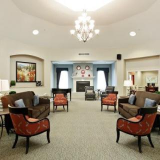 A spacious and elegantly decorated living room featuring a chandelier, multiple seating options, and a fireplace.